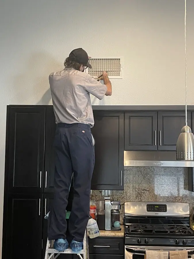 Technician inspecting an air vent during HVAC service in Lake of the Pines
